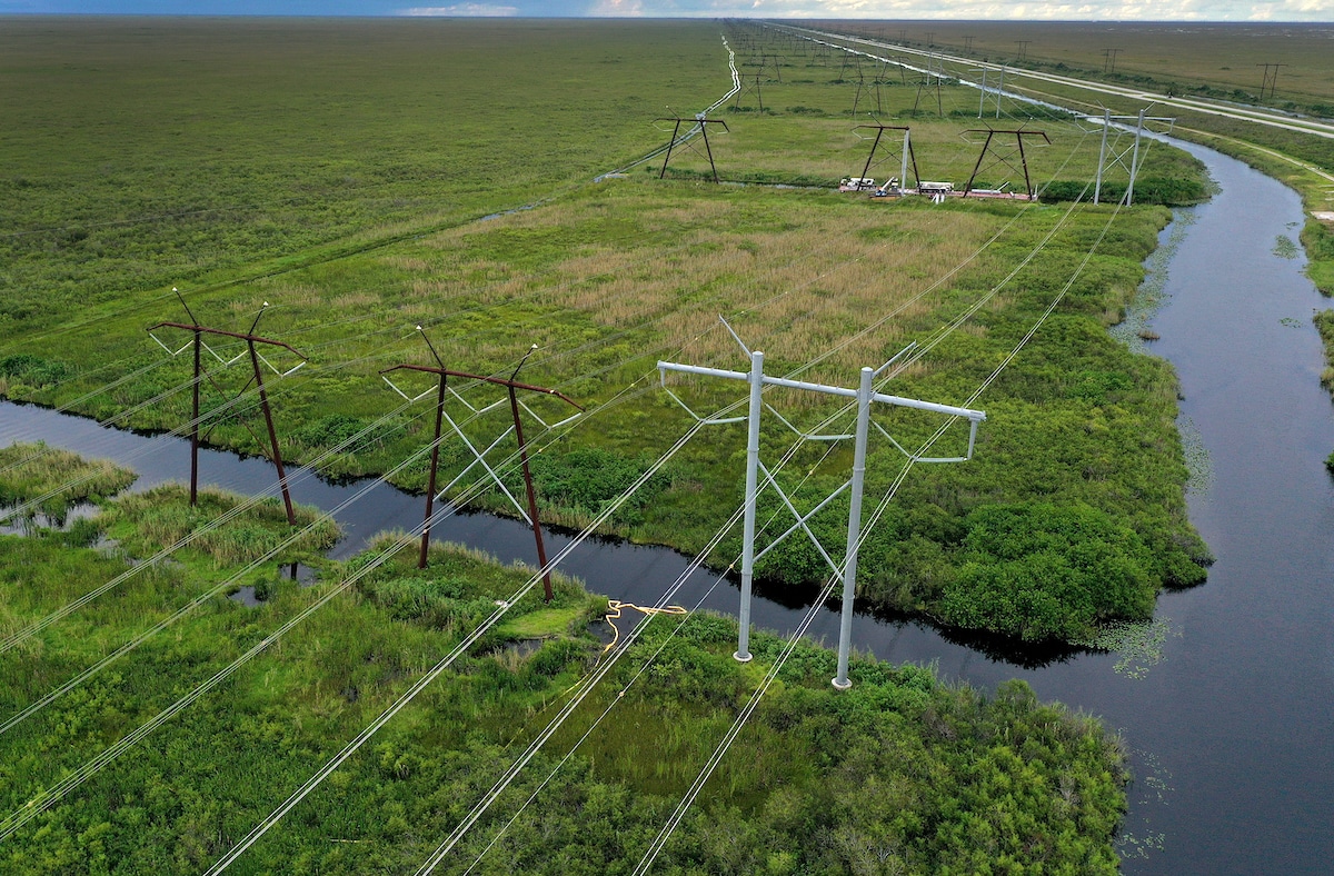 In an aerial view, electric power lines are attached to the transmission tower along the power grid in the Everglades, Florida